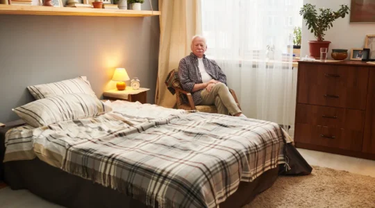 Chambre personnalisée d'EHPAD avec résidente âgée assise dans son fauteuil personnel entourée de photos de famille et objets familiers